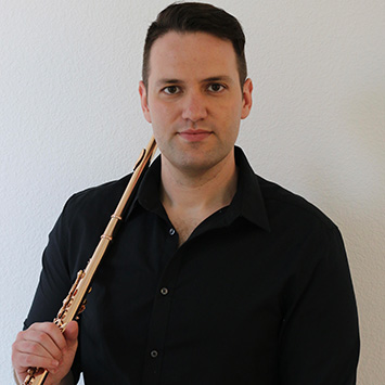 white man in black collared shirt resting a flute on his right shoulder