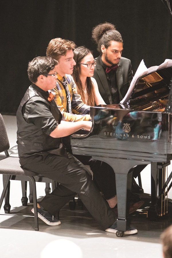 four students paling a grand piano